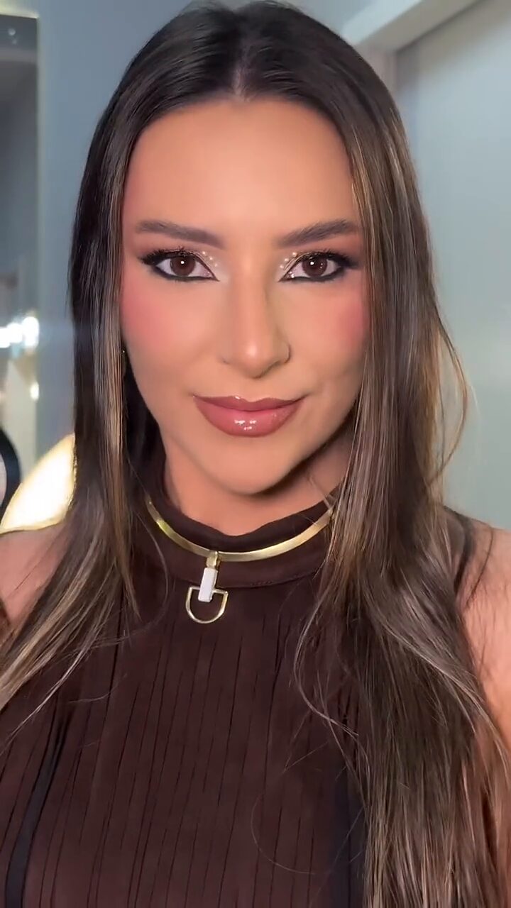 Vitória em close, com a maquiagem pronta e um colar dourado no pescoço.