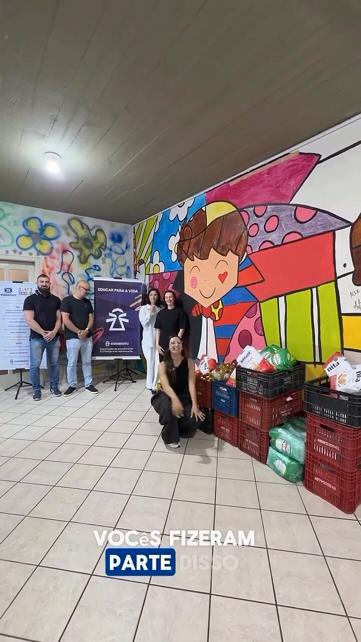 Caixas de alimentos arrecadados enfileiradas ao lado das pessoas que participaram da ação.